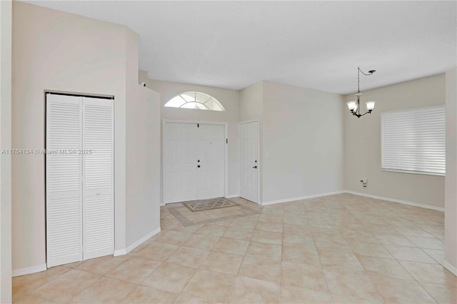 foyer entrance with a chandelier, baseboards, and light tile patterned flooring