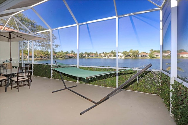 view of patio with a lanai and a water view