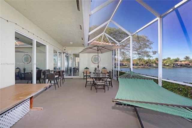 view of patio / terrace with a lanai, outdoor dining area, and a water view