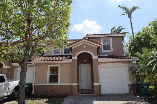 mediterranean / spanish home with stucco siding, a tiled roof, and decorative driveway