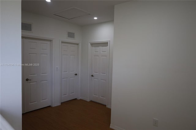 hallway with recessed lighting, wood finished floors, visible vents, and baseboards