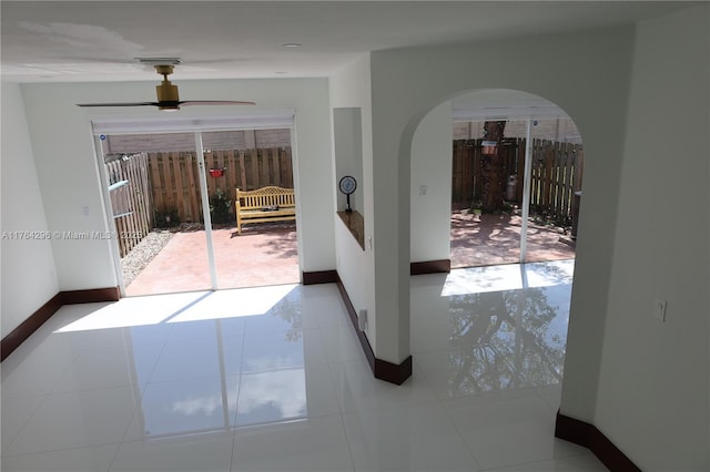 interior space with tile patterned flooring, plenty of natural light, baseboards, and arched walkways