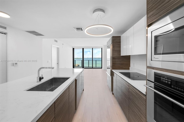 kitchen with a wall of windows, visible vents, a sink, appliances with stainless steel finishes, and modern cabinets