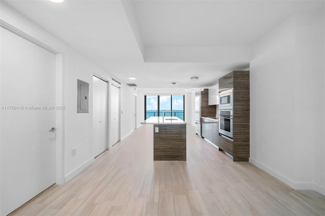 interior space featuring light wood-style flooring, built in microwave, light countertops, stainless steel oven, and modern cabinets