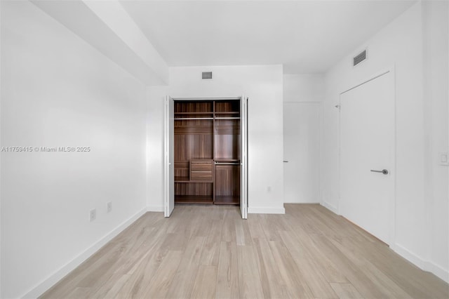 unfurnished bedroom featuring visible vents, baseboards, light wood finished floors, and a closet