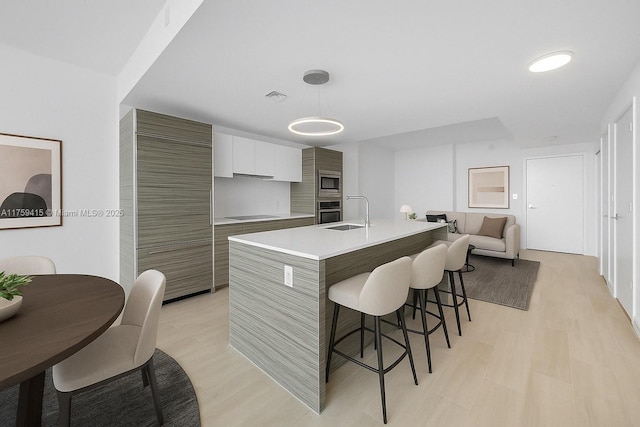 kitchen featuring modern cabinets, visible vents, a breakfast bar, light countertops, and stainless steel appliances