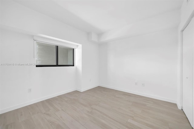 spare room with baseboards and wood finished floors