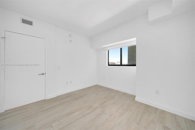 empty room with visible vents, baseboards, and light wood-style floors