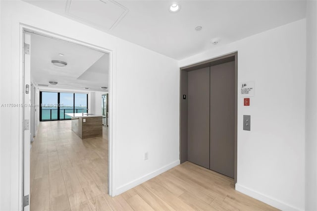 corridor with elevator, baseboards, light wood-type flooring, and recessed lighting