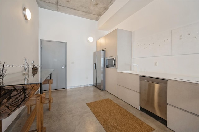 kitchen with stainless steel appliances, finished concrete floors, and light countertops