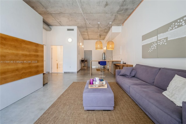 unfurnished living room with visible vents, a high ceiling, and finished concrete flooring