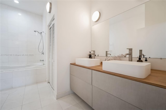 bathroom featuring a sink, tiled shower / bath, double vanity, and tile patterned flooring