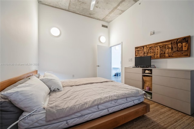 bedroom featuring visible vents, a high ceiling, and ceiling fan