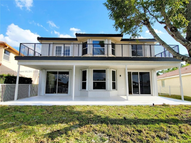 rear view of property featuring a yard, a patio, a balcony, and fence