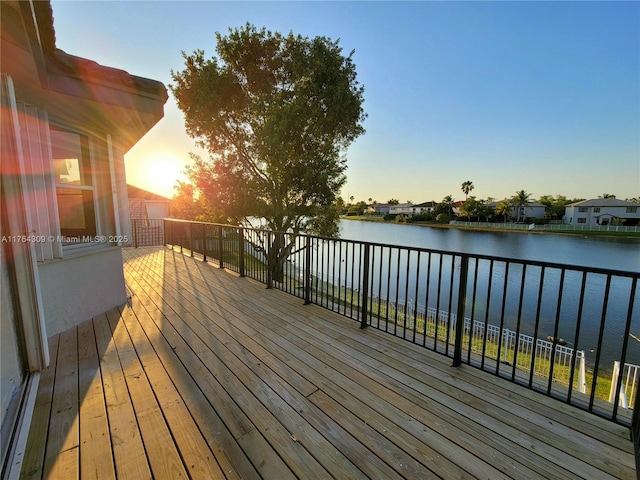 deck at dusk featuring a water view