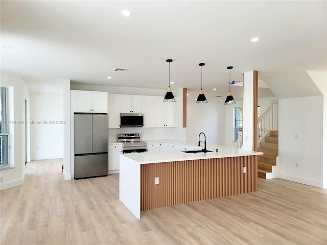 kitchen with light wood finished floors, light countertops, recessed lighting, appliances with stainless steel finishes, and a sink