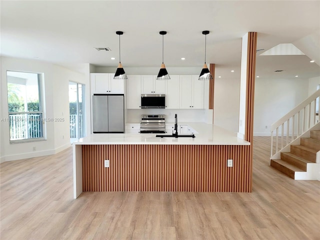 kitchen featuring light countertops, visible vents, light wood finished floors, and stainless steel appliances