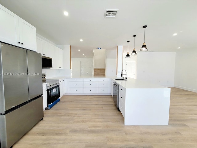 kitchen featuring light wood finished floors, visible vents, appliances with stainless steel finishes, a peninsula, and a sink