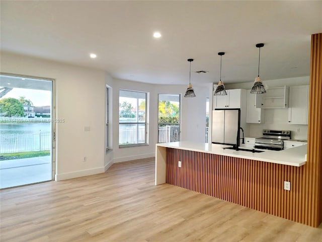 kitchen featuring light countertops, light wood-type flooring, appliances with stainless steel finishes, white cabinets, and a sink