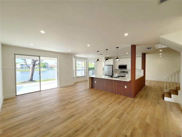 kitchen with light wood-style flooring, open floor plan, recessed lighting, appliances with stainless steel finishes, and light countertops