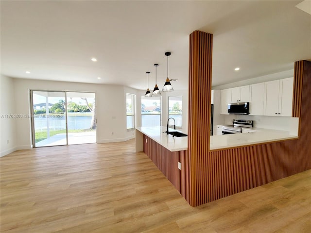 kitchen featuring light wood-type flooring, a sink, open floor plan, appliances with stainless steel finishes, and light countertops