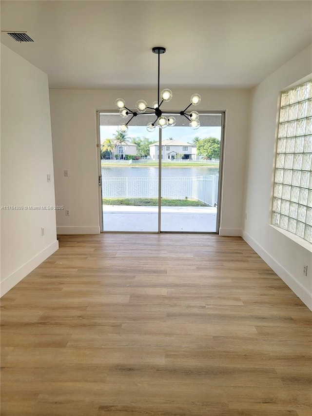 unfurnished dining area featuring visible vents, baseboards, a chandelier, and light wood finished floors