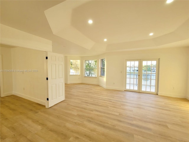 unfurnished room with recessed lighting, a tray ceiling, baseboards, and light wood-style flooring