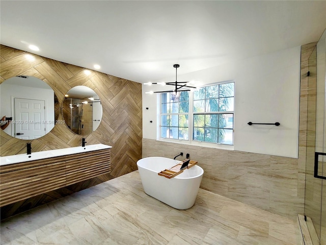 full bath featuring a shower stall, a freestanding bath, tile walls, and an inviting chandelier