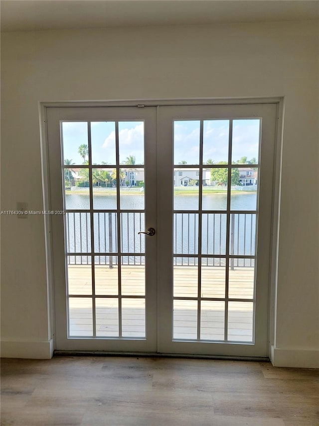 doorway with french doors, light wood-style floors, and a water view