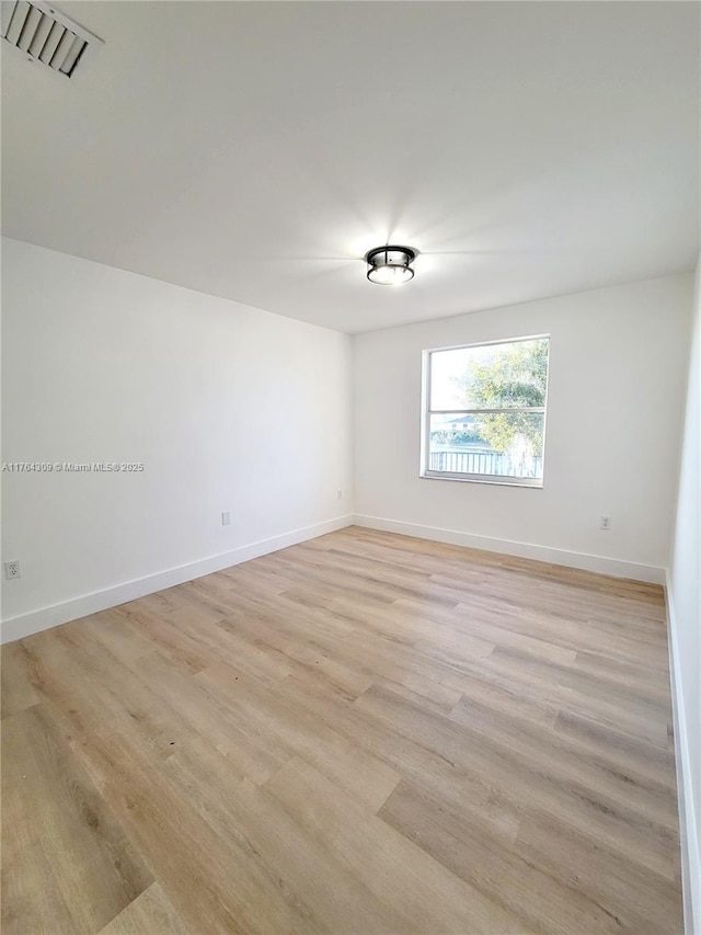 unfurnished room featuring visible vents, baseboards, and light wood-style floors