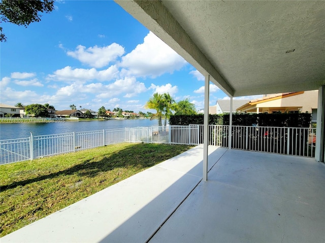 view of patio with fence and a water view