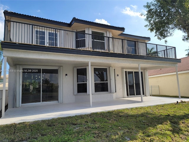 rear view of property with stucco siding, a patio, and a balcony