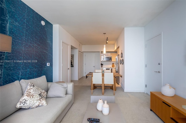 living room featuring baseboards, light carpet, an accent wall, and wallpapered walls