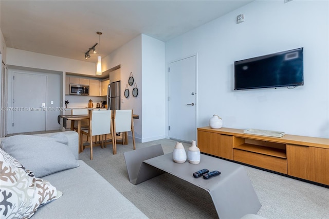 living area with baseboards, light colored carpet, and track lighting