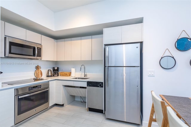 kitchen featuring white cabinets, appliances with stainless steel finishes, light countertops, and a sink