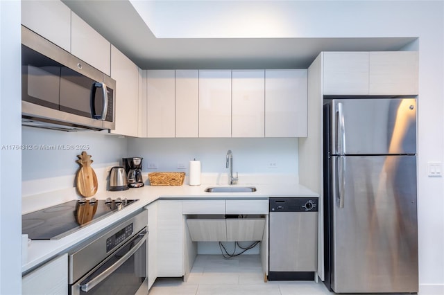 kitchen featuring a sink, light countertops, white cabinets, appliances with stainless steel finishes, and modern cabinets