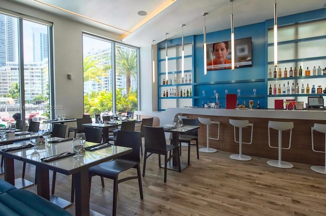 dining space featuring plenty of natural light, wet bar, and wood finished floors