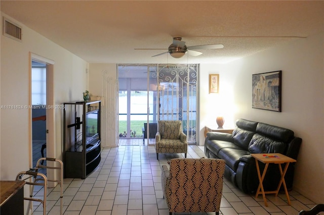 living room with light tile patterned floors, visible vents, a textured ceiling, and ceiling fan