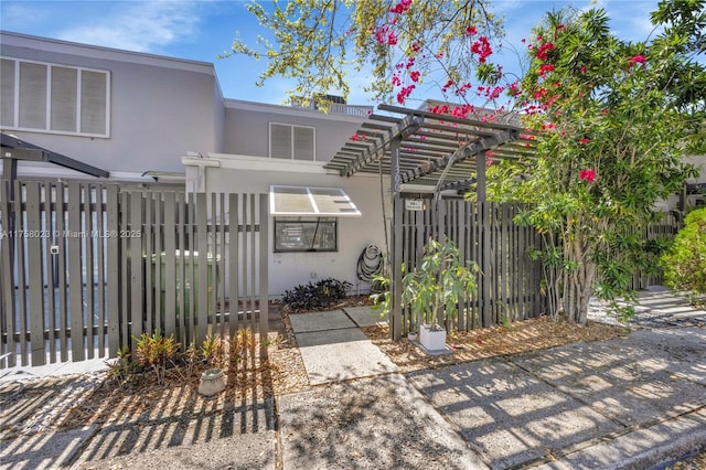 exterior space with a fenced front yard, stucco siding, and a pergola