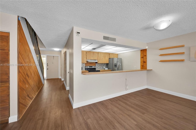 kitchen featuring wood finished floors, visible vents, stainless steel appliances, decorative backsplash, and under cabinet range hood