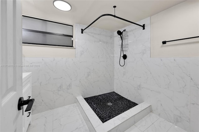 bathroom with marble finish floor, tiled shower, and tile walls