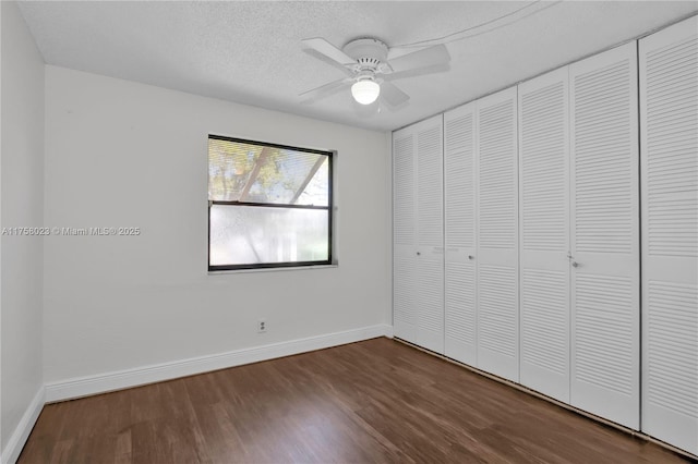 unfurnished bedroom featuring dark wood finished floors, ceiling fan, a textured ceiling, and baseboards