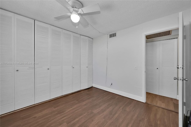 unfurnished bedroom with visible vents, a ceiling fan, a textured ceiling, dark wood-style floors, and baseboards