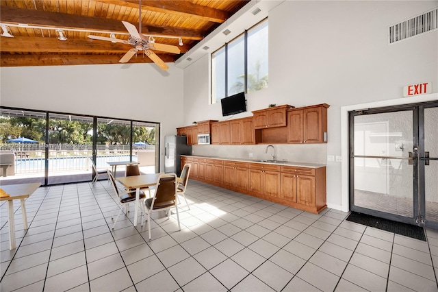 unfurnished dining area featuring visible vents, a ceiling fan, a sink, light tile patterned floors, and wood ceiling