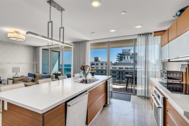 kitchen with wallpapered walls, stainless steel appliances, a sink, expansive windows, and brown cabinets