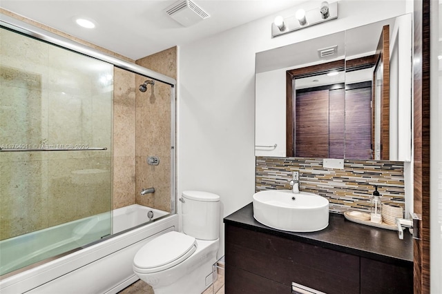 full bath featuring vanity, visible vents, shower / bath combination with glass door, toilet, and backsplash