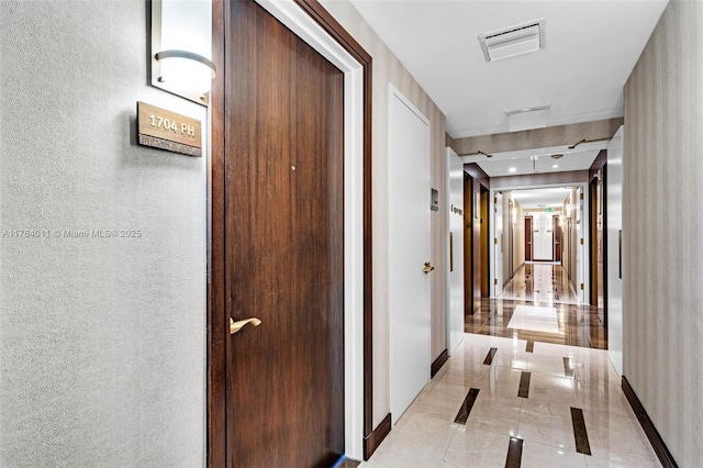 hall with visible vents, marble finish floor, and a textured wall