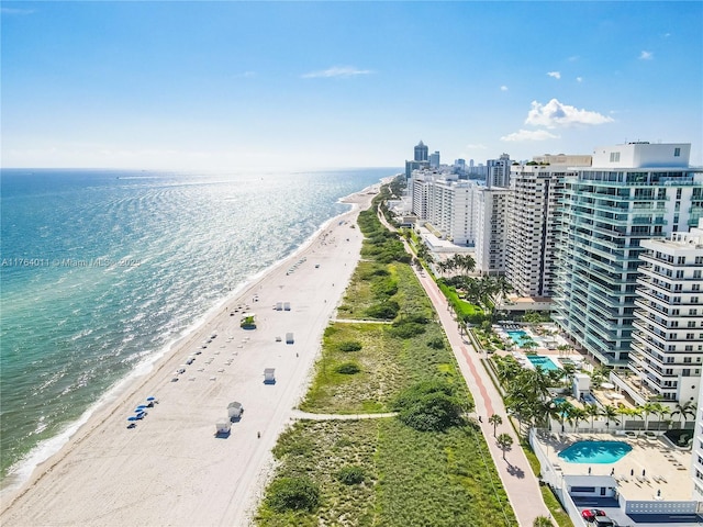 drone / aerial view featuring a water view, a city view, and a beach view