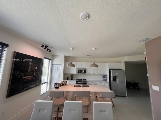 dining area featuring light tile patterned floors, visible vents, and a textured ceiling