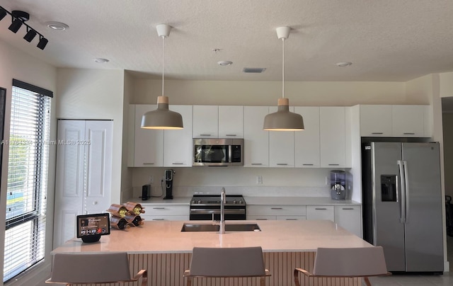 8001 NW 41st St Unit F-207, Doral, FL 33166 - kitchen featuring appliances with stainless steel finishes, a sink, a textured ceiling, light countertops, and white cabinets
